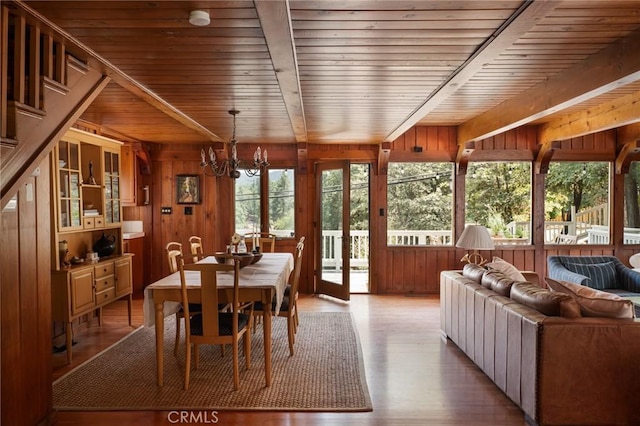 dining space featuring a chandelier, light hardwood / wood-style flooring, wooden ceiling, and wood walls