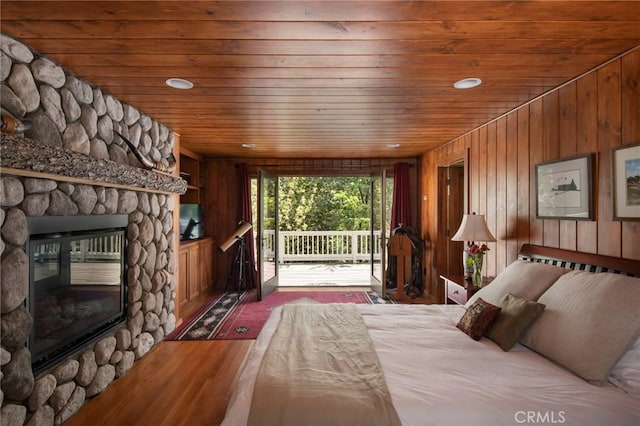 unfurnished bedroom featuring wooden ceiling, dark hardwood / wood-style floors, access to outside, wooden walls, and a fireplace