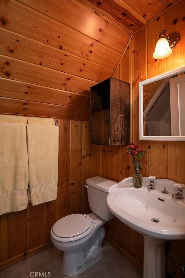 bathroom with toilet, wooden ceiling, wooden walls, and vaulted ceiling