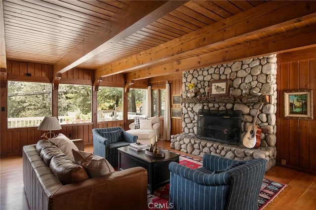 sunroom featuring beamed ceiling, a stone fireplace, plenty of natural light, and wood ceiling