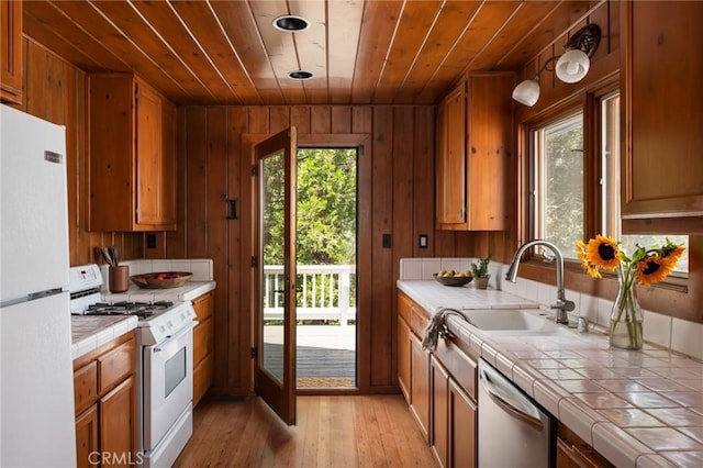 kitchen featuring white appliances, tile countertops, light hardwood / wood-style flooring, and wooden walls