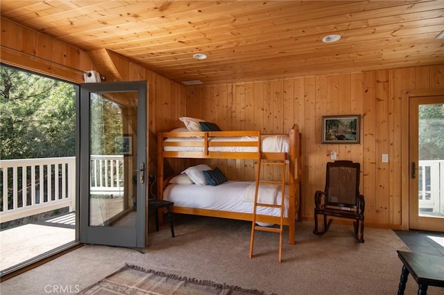 unfurnished bedroom featuring access to exterior, carpet floors, wooden walls, and wood ceiling