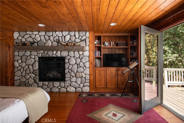 bedroom featuring a stone fireplace, wood walls, access to outside, wood ceiling, and light wood-type flooring