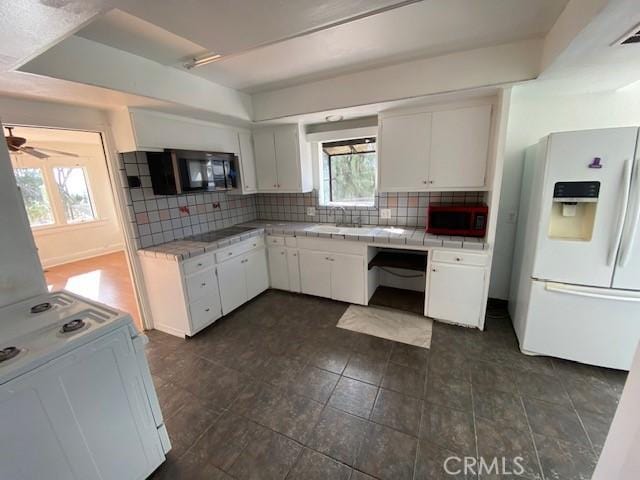 kitchen featuring white cabinetry, backsplash, and black appliances