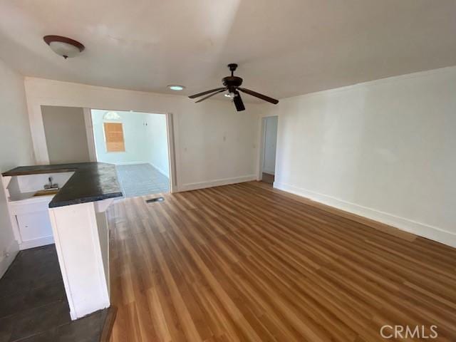 unfurnished living room with ceiling fan and dark wood-type flooring