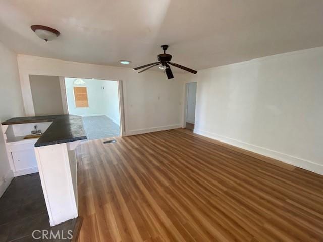 unfurnished living room featuring dark wood-type flooring and ceiling fan