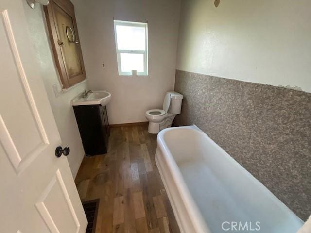 bathroom featuring hardwood / wood-style floors, a bathtub, vanity, and toilet