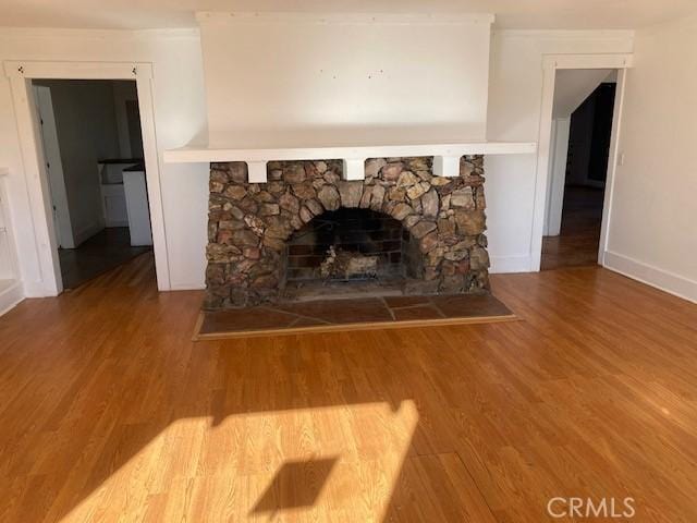 interior details with wood-type flooring and a stone fireplace