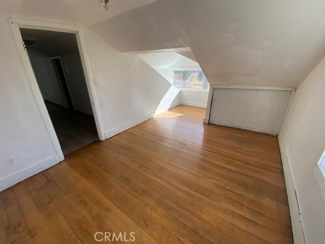 additional living space featuring lofted ceiling and light wood-type flooring