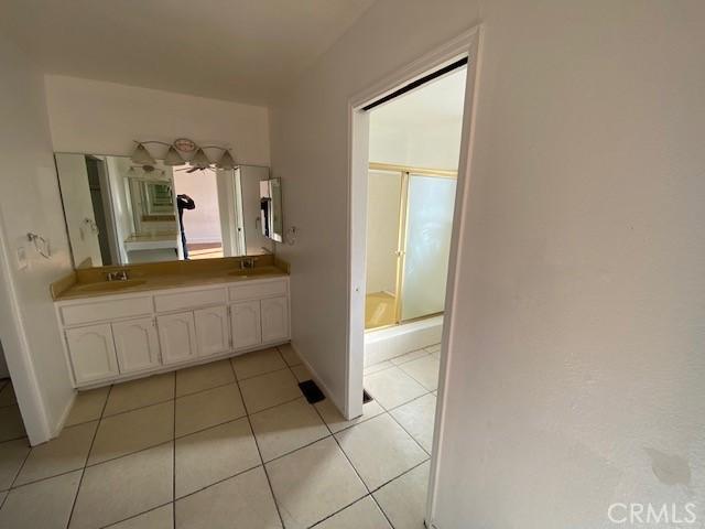 bathroom with an enclosed shower, vanity, and tile patterned flooring