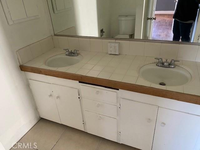 bathroom with toilet, tile patterned floors, backsplash, and vanity