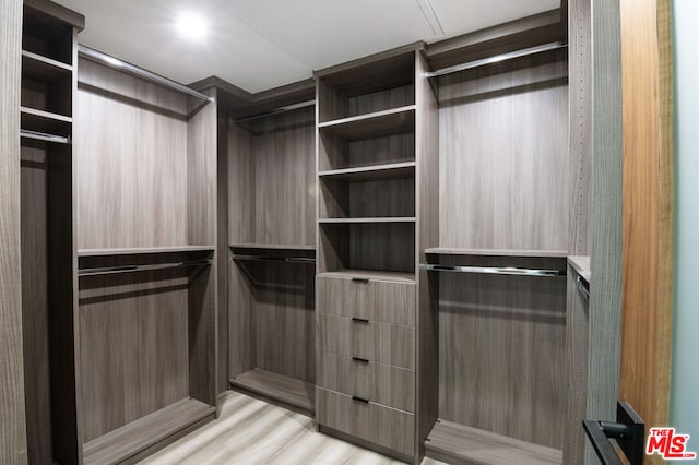 walk in closet with light hardwood / wood-style flooring