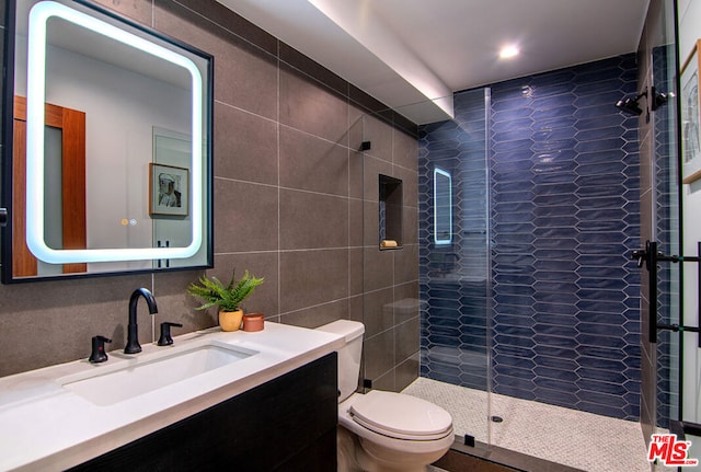 bathroom featuring an enclosed shower, vanity, toilet, and tile walls