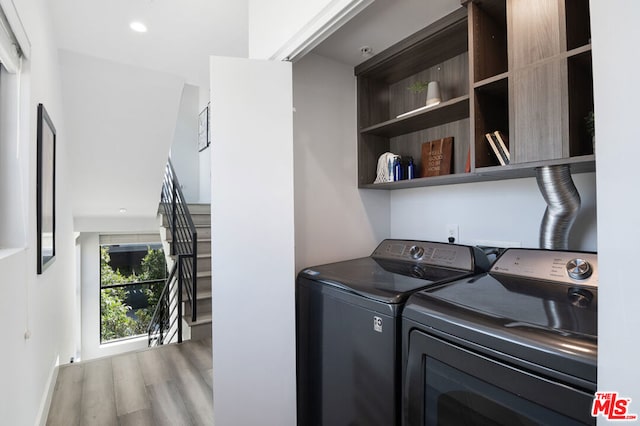 clothes washing area with washer and dryer and hardwood / wood-style flooring