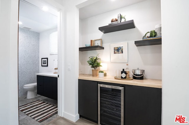 bar with wine cooler, light hardwood / wood-style flooring, and tile walls