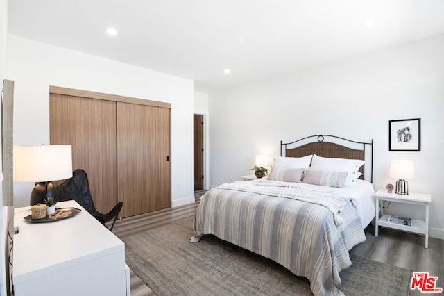 bedroom with dark wood-type flooring and a closet