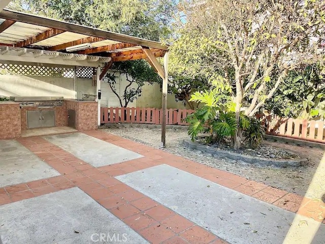 view of patio with area for grilling and a pergola