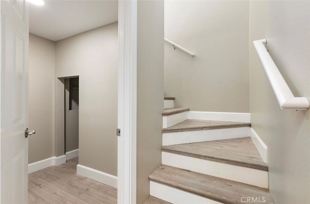 stairs with wood finished floors and baseboards