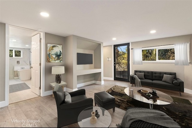 living room with light wood-style floors, baseboards, and recessed lighting