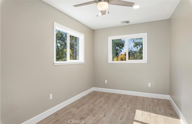 unfurnished room with light wood-style flooring, a ceiling fan, visible vents, and baseboards