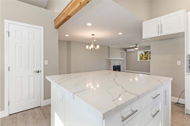 kitchen with light stone countertops, pendant lighting, white cabinets, and a center island