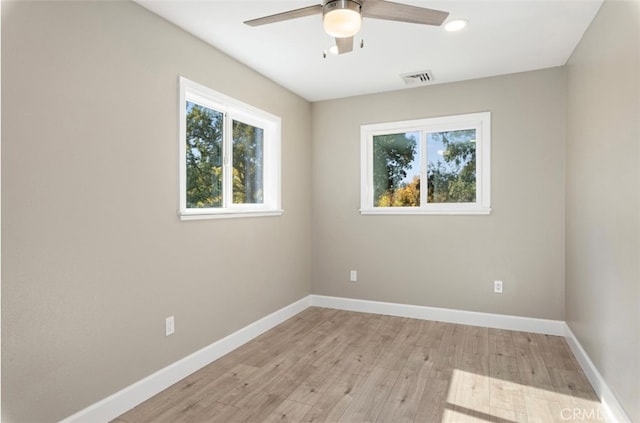 empty room with a ceiling fan, visible vents, light wood-style flooring, and baseboards