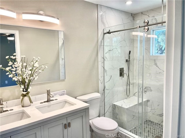 bathroom featuring double vanity, a marble finish shower, toilet, and a sink