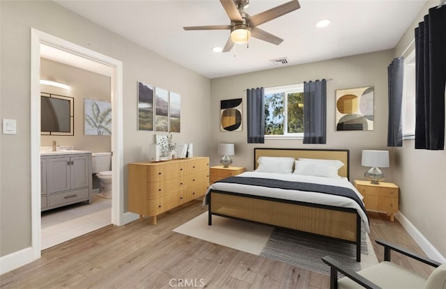 bedroom featuring light wood finished floors, visible vents, baseboards, ensuite bath, and recessed lighting