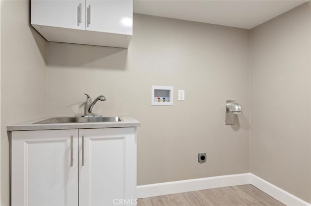 clothes washing area featuring hookup for a washing machine, sink, light hardwood / wood-style floors, electric dryer hookup, and cabinets