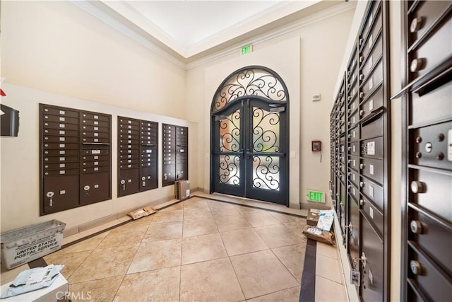 tiled entrance foyer with mail boxes, a towering ceiling, and crown molding