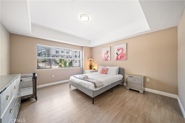 bedroom featuring a tray ceiling and light wood-type flooring