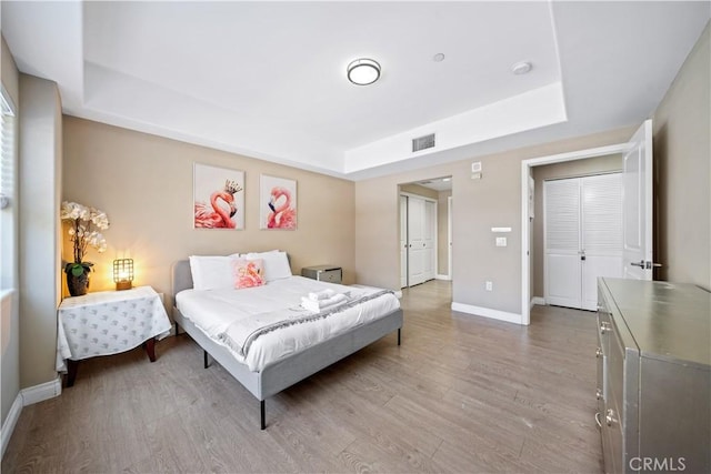 bedroom with a raised ceiling and light hardwood / wood-style flooring