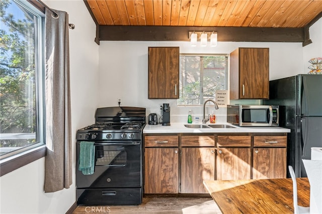 kitchen featuring wood ceiling, plenty of natural light, sink, and black gas range oven