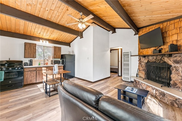 living room with vaulted ceiling with beams, ceiling fan, and light hardwood / wood-style flooring