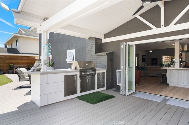 wooden terrace with ceiling fan, area for grilling, an outdoor bar, and exterior kitchen