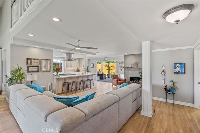 living room with a large fireplace, plenty of natural light, light hardwood / wood-style floors, and ornamental molding