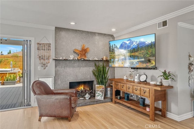 living area featuring a fireplace, wood-type flooring, and ornamental molding