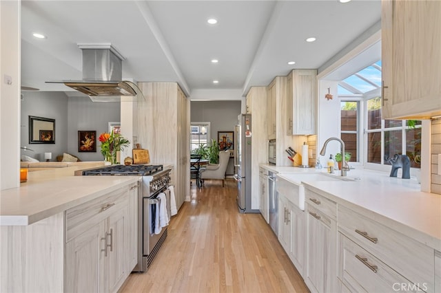 kitchen featuring kitchen peninsula, appliances with stainless steel finishes, light wood-type flooring, light brown cabinetry, and exhaust hood