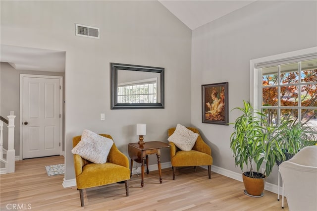 living area with a healthy amount of sunlight, light wood-type flooring, and high vaulted ceiling