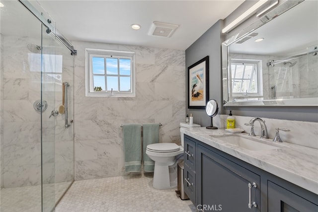 bathroom with vanity, toilet, a shower with shower door, and tile walls