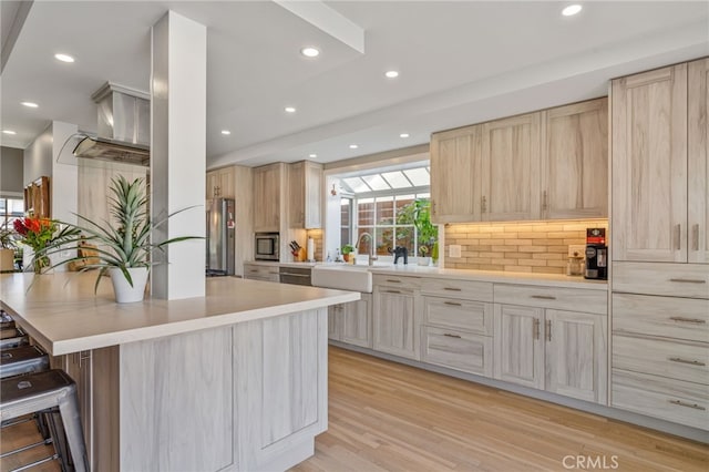 kitchen with light brown cabinetry, sink, and a breakfast bar