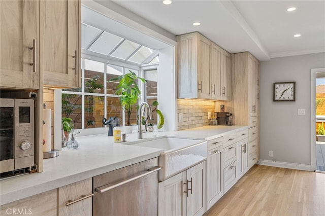 kitchen with light brown cabinetry, light hardwood / wood-style flooring, stainless steel appliances, and sink