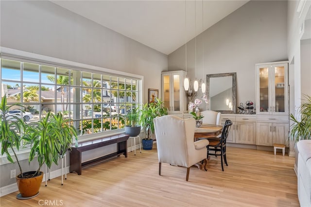 dining space featuring light hardwood / wood-style flooring, high vaulted ceiling, and a healthy amount of sunlight