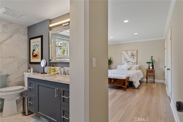 interior space featuring ornamental molding, toilet, vanity, tile walls, and hardwood / wood-style flooring