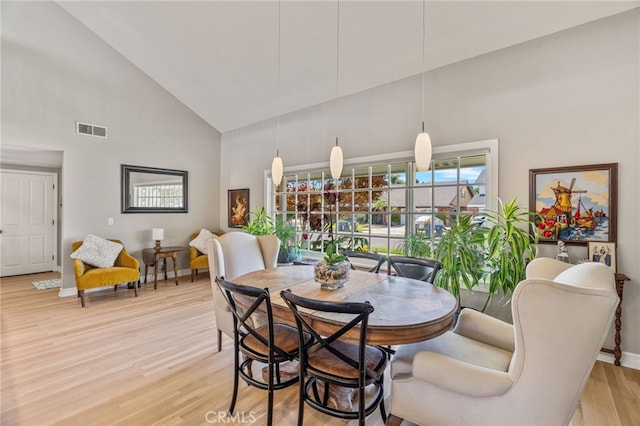 dining room with light wood-type flooring and high vaulted ceiling