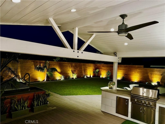 view of patio with ceiling fan, area for grilling, exterior kitchen, and a wooden deck