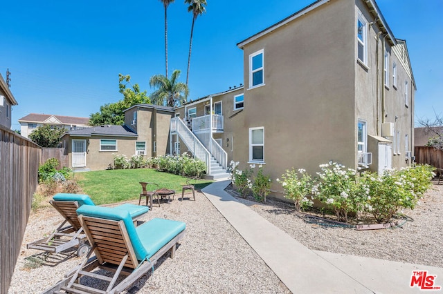 rear view of property with a lawn and cooling unit