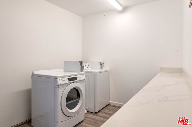 clothes washing area featuring washer and clothes dryer and light wood-type flooring