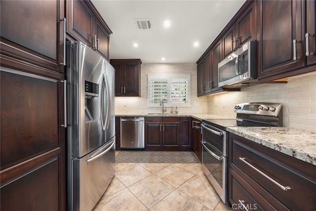 kitchen featuring backsplash, stainless steel appliances, light stone counters, and sink