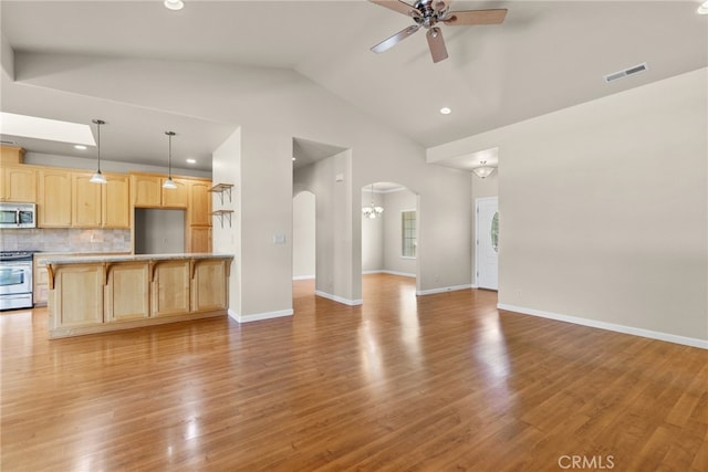 kitchen featuring appliances with stainless steel finishes, backsplash, light brown cabinets, ceiling fan, and hardwood / wood-style floors